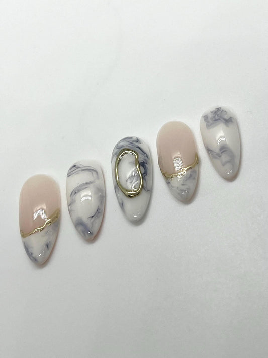 Handmade decorative press-on nails with marble and gold accents on a white background