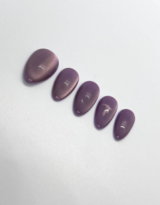 Handmade purple glittery press-on nails with 7 Purple Cat Eye design on a white background