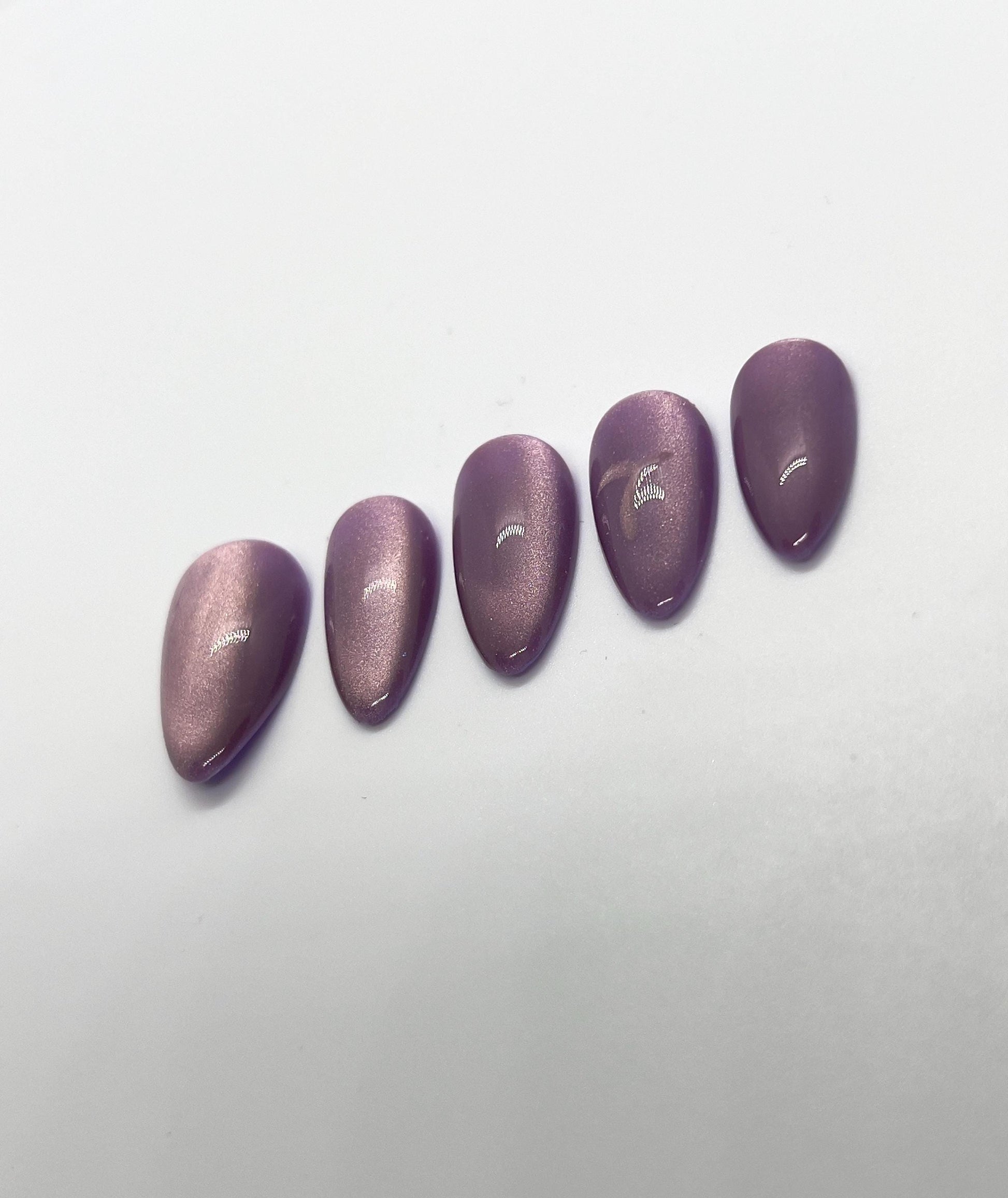 Handmade purple glittery press-on nails with 7 Purple Cat Eye design on a white background