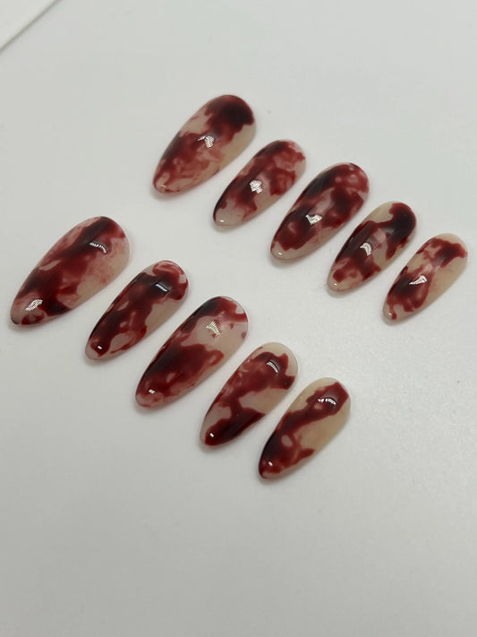 Handmade maroon and beige marbled press-on nails displayed on a white background
