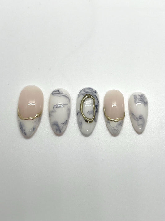 Handmade decorative press-on nails with marble and gold accents on a white background