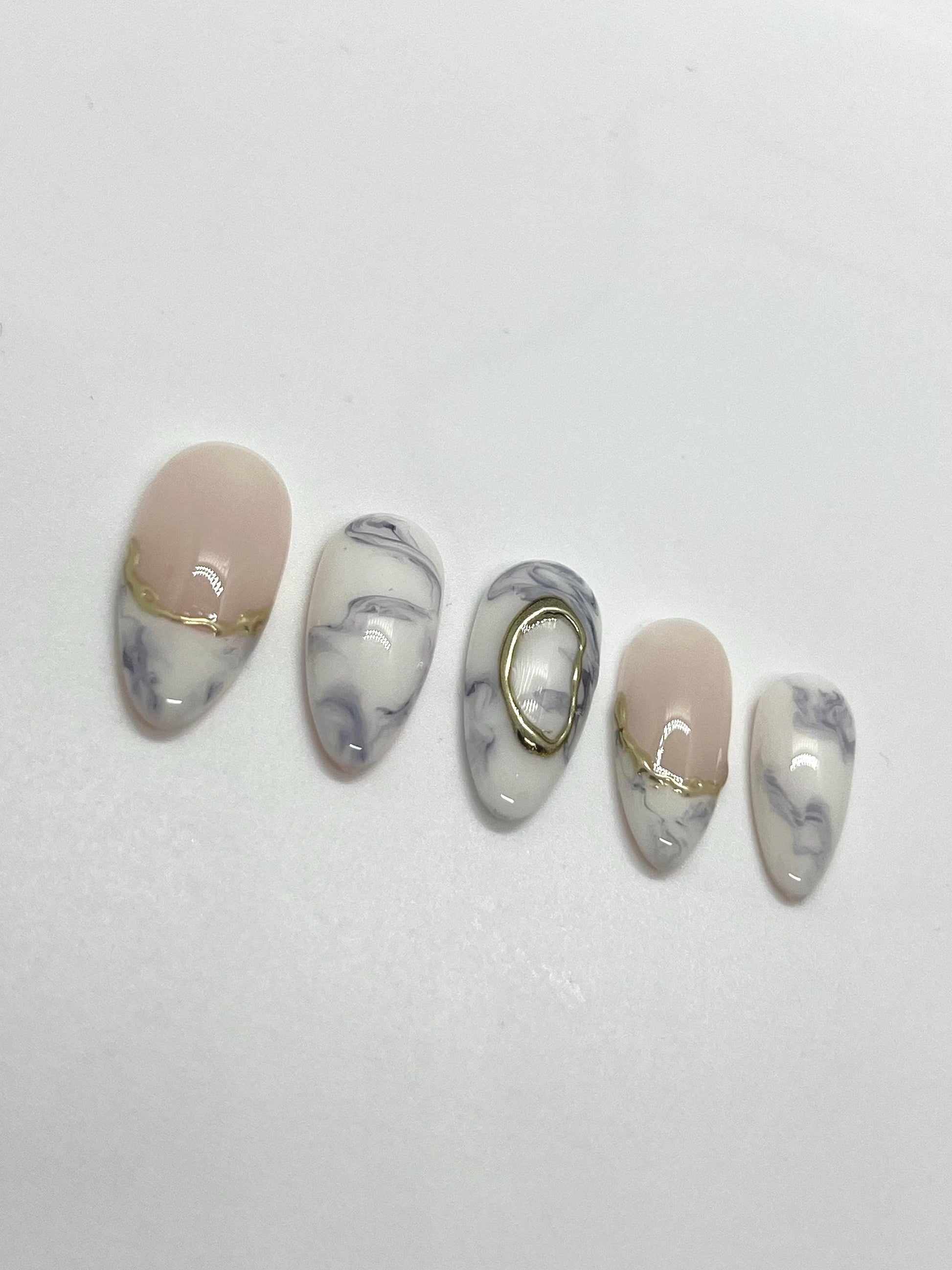 Handmade decorative press-on nails with marble and gold accents on a white background