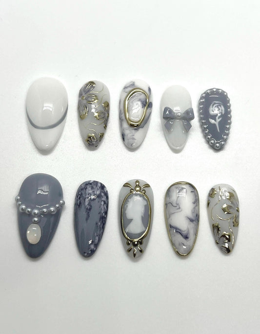 This Bridgerton-inspired handmade press-on nail set captures the elegance and charm of Regency-era balls and whispered society secrets. Featuring soft pastels, pearl-like accents, and delicate gold detailing, these nails offer a refined yet romantic look—perfect for tea parties, formal events, or anyone ready to feel like the season’s most admired diamond.