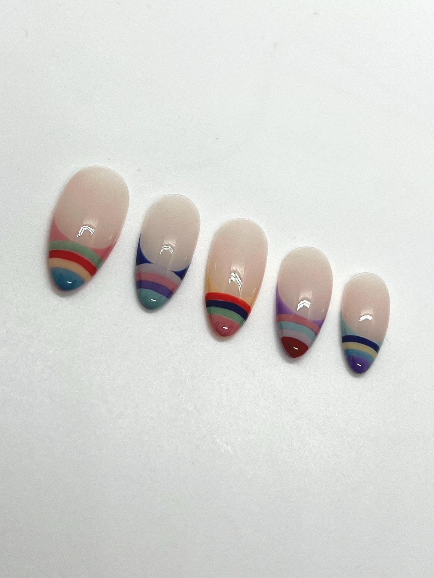 Handmade press-on nails with multicolored striped designs on a white background
