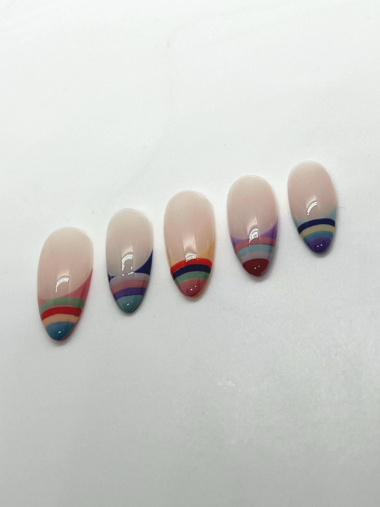 Handmade press-on nails with multicolored striped designs on a white background