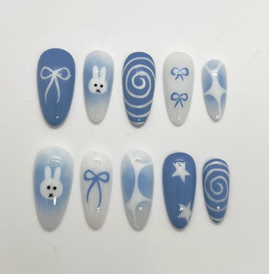 Handmade blue press-on nails with Miffy-inspired design on a white background