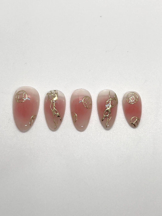 Handmade pink press-on nail samples with gold accents displayed on a white background