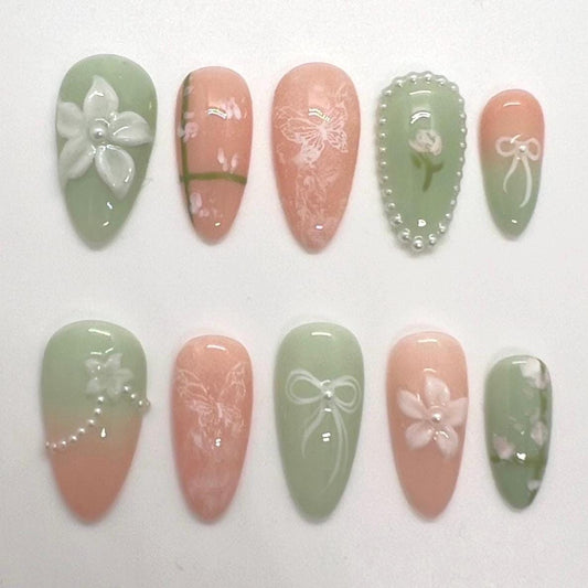 Handmade decorative press-on nails with floral and bow designs on a white background